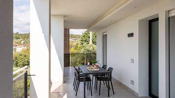 Un balcone con un tavolo apparecchiato per due persone, sedie e una bottiglia di vino.