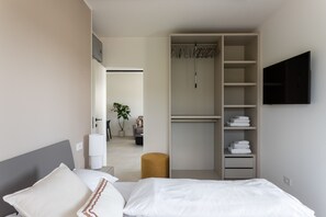 Ein Schlafzimmer mit einem Bett, einem Kleiderschrank, einem Fernseher und einer Pflanze.