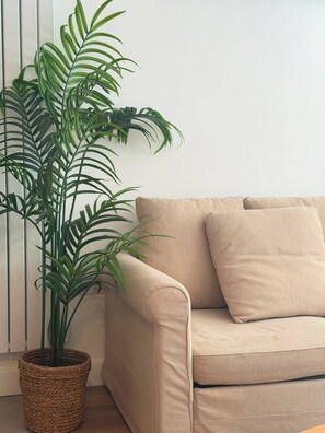 A room with a beige sofa and a large potted plant. - Chalk Farm- Camden 3 bedrooms Complex (London)