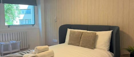 Un dormitorio moderno con una cama grande, una mesita de noche, una ventana con vistas y una lámpara de techo.