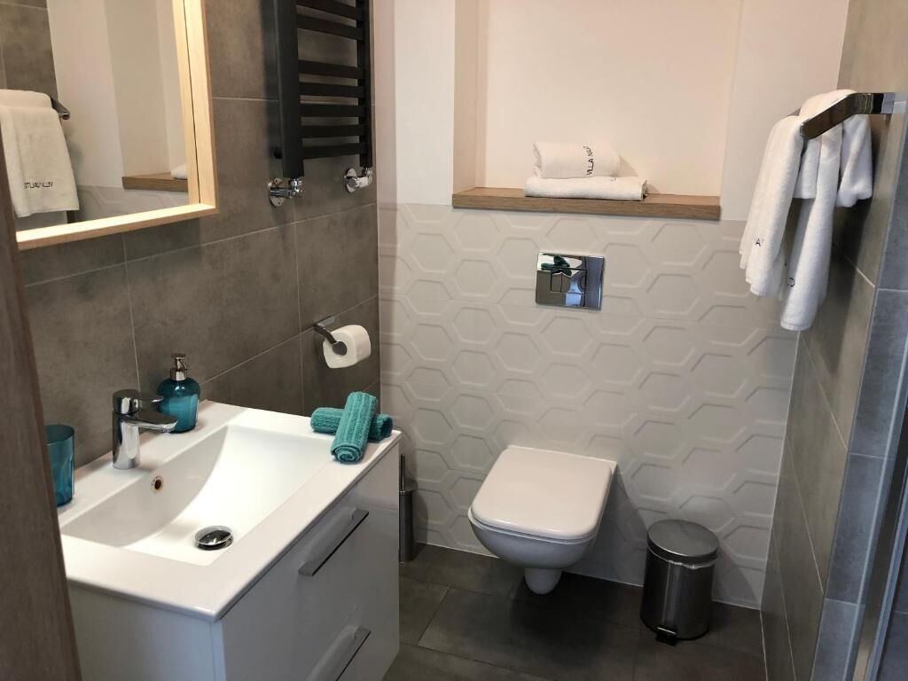 A bathroom with a white sink, a toilet, a towel rack, and a mirror.