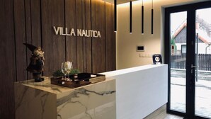 Una recepción con un panel de madera de fondo y el nombre 'VILLA NAUTICA' en el centro.