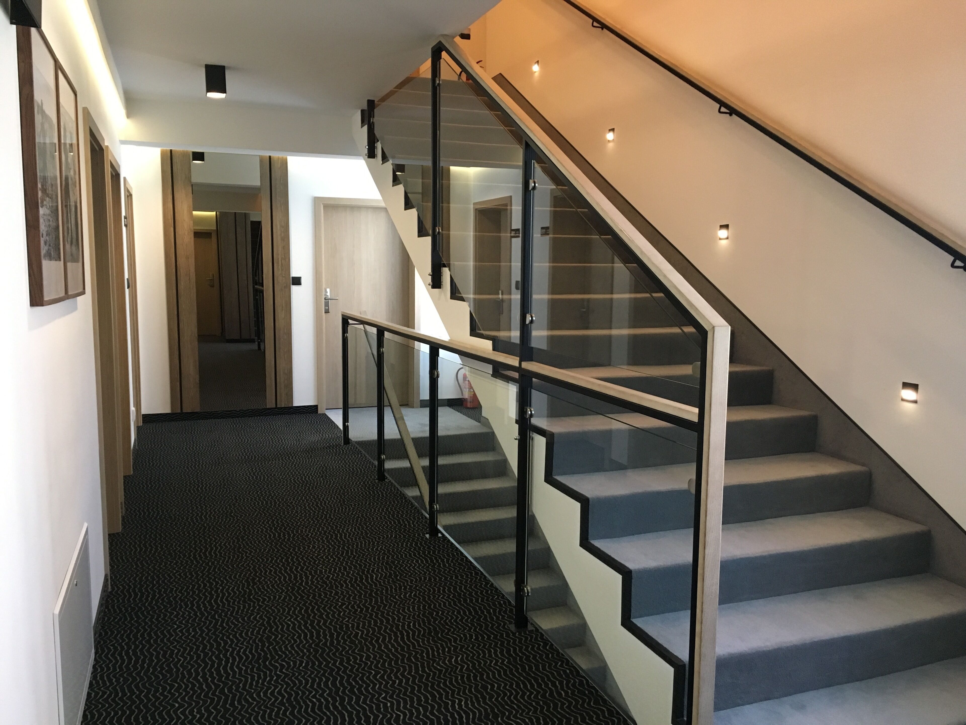 A modern staircase with glass railings and carpeted steps.
