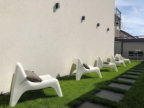Mobiliario exterior con pared blanca y césped.