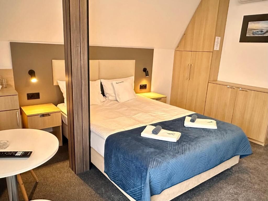 A hotel room with a bed, bedside tables, a small round table, and a wardrobe.