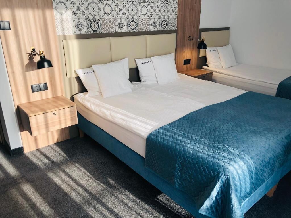 Una habitación de hotel con cama, mesitas de noche y un papel tapiz estampado.