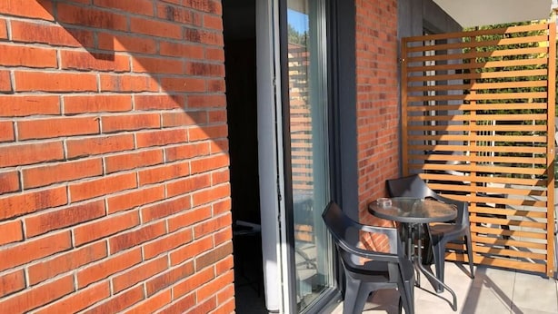 Un balcón con puerta de vidrio, una mesa pequeña y dos sillas.
