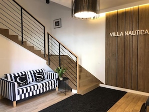 Un interior moderno con una escalera, un sofá a rayas negro y blanco, una pared de acento de madera y una alfombra negra.