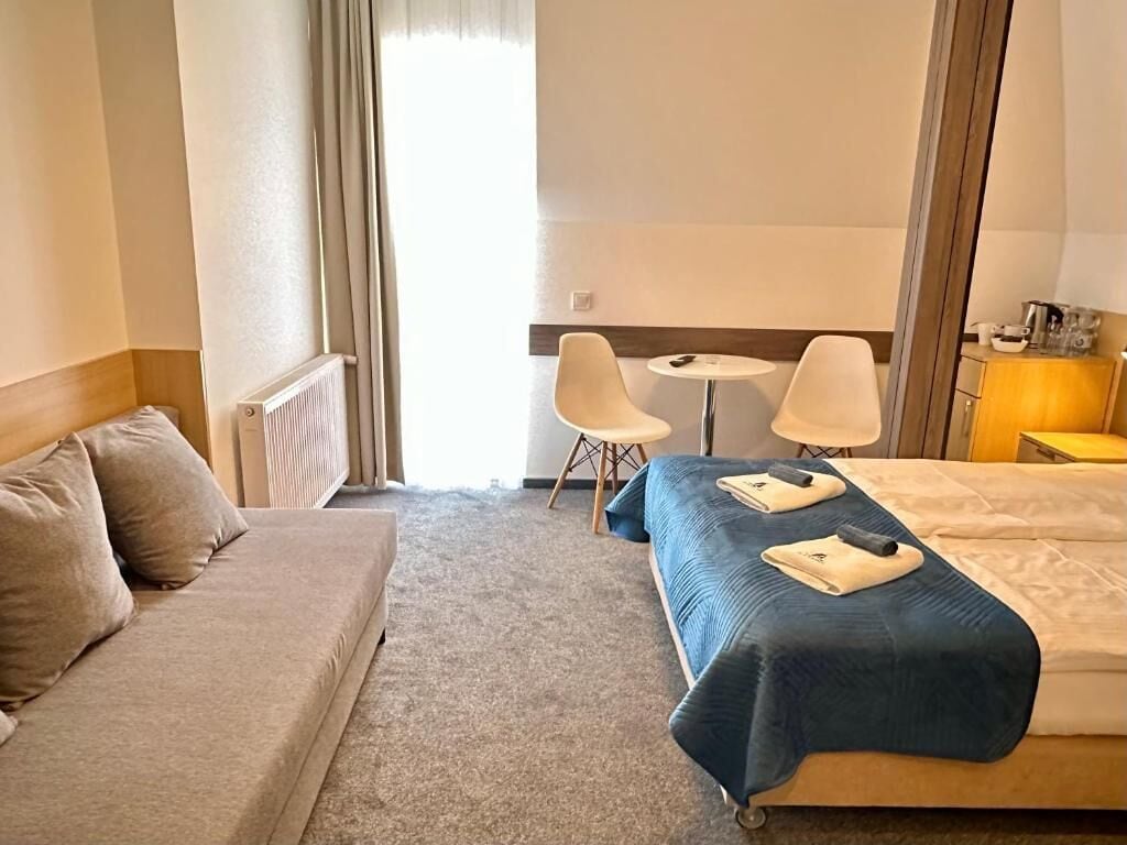 A hotel room with a bed, a sofa, a small table, and a chair.