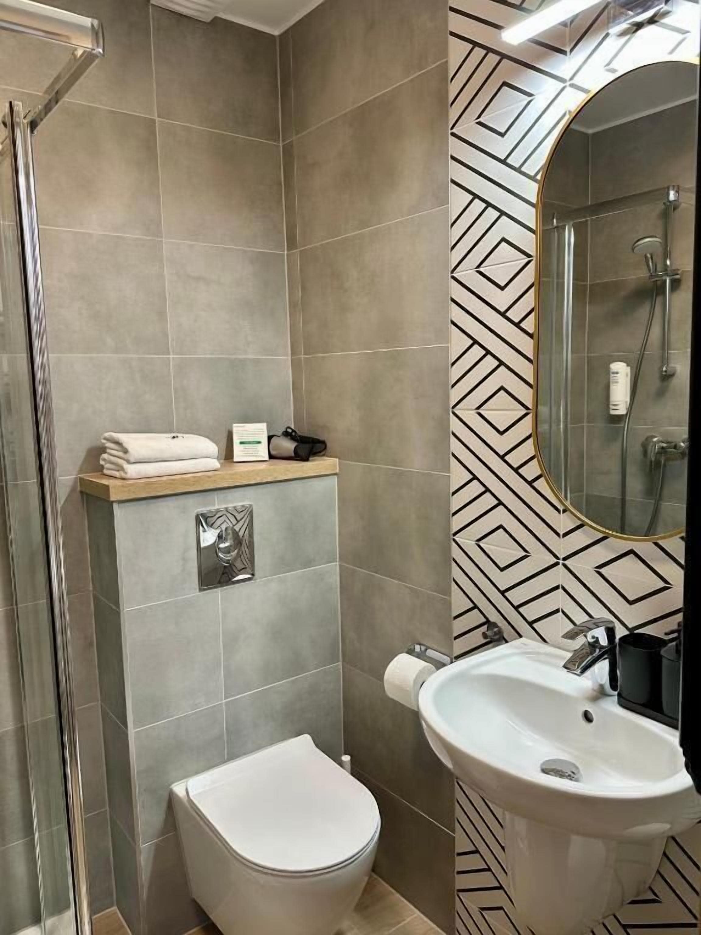 Un baño con ducha, inodoro, lavabo y espejo.