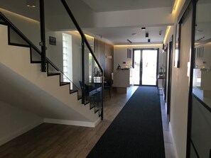 Un interior moderno con una escalera, un mostrador de recepción y vistas a través de un ventanal.