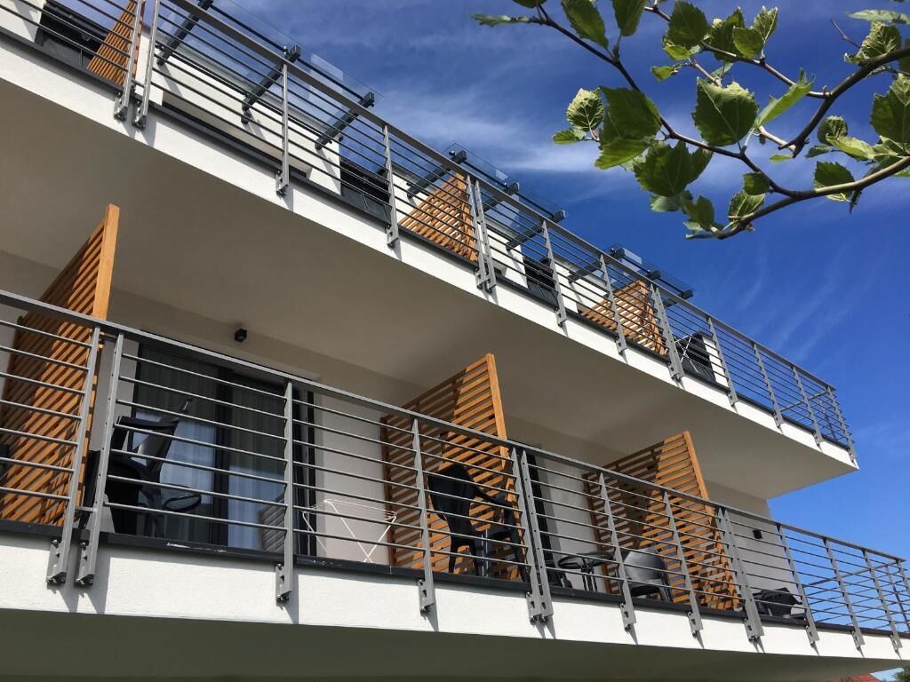 Un edificio de varios pisos con balcones, barandillas metálicas y contraventanas de madera.