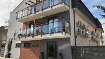 Ein modernes, zweistöckiges Gebäude mit einem Glasbalkon, einer Schilder an der Fassade mit der Aufschrift 'Villa Nautica' und mehreren Klimaanlagen an der Außenwand.