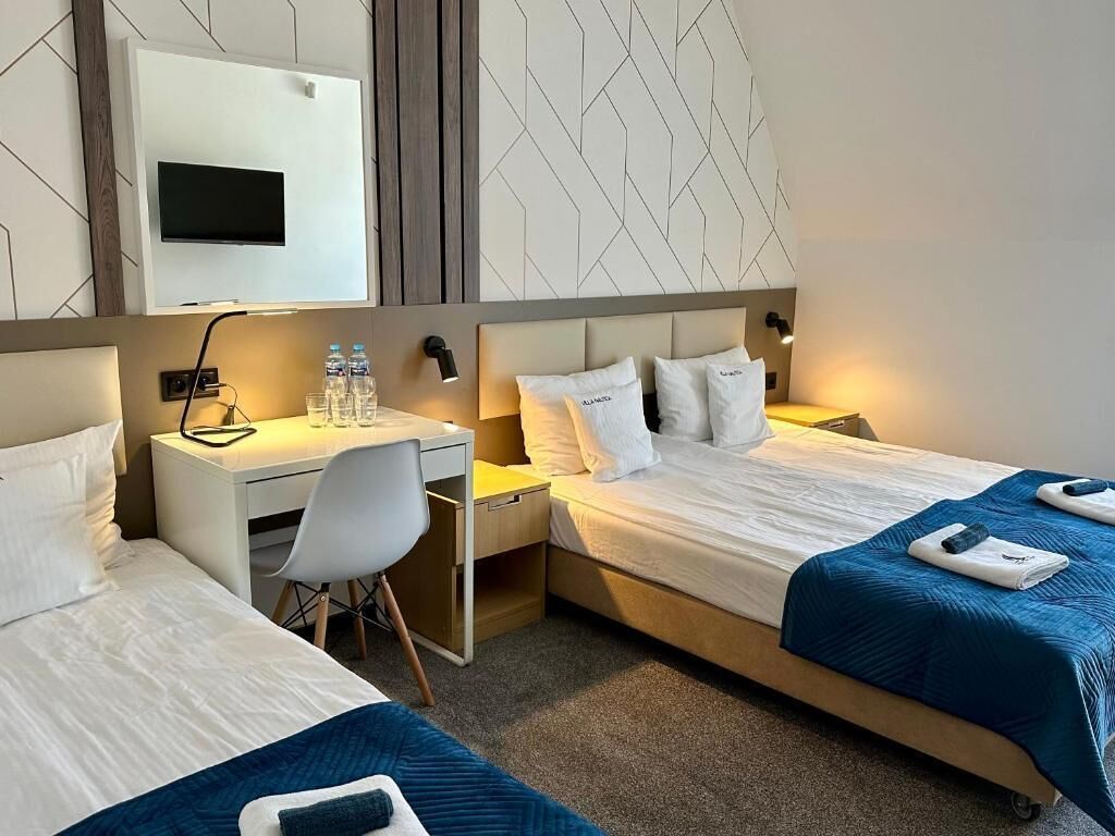Een hotelkamer met twee bedden, een bureau en een aan de muur bevestigde televisie.