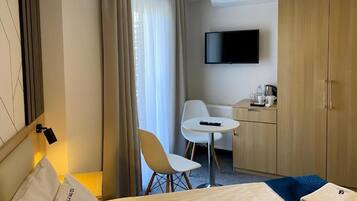 A hotel room with a bed, a desk, a chair, a television, and a wardrobe.