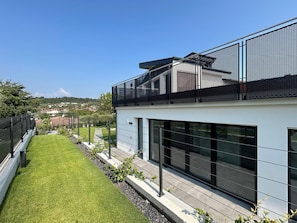 A modern building with a flat roof, large windows, and a balcony with a mesh railing. - Casa Franzosi - Leccino Luxury (Puegnago sul Garda)