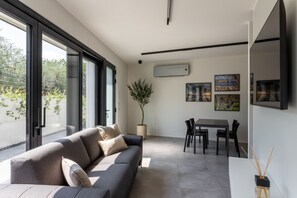 Un salon moderne avec un canapé, une table à manger et des chaises, ainsi qu’une plante en pot.