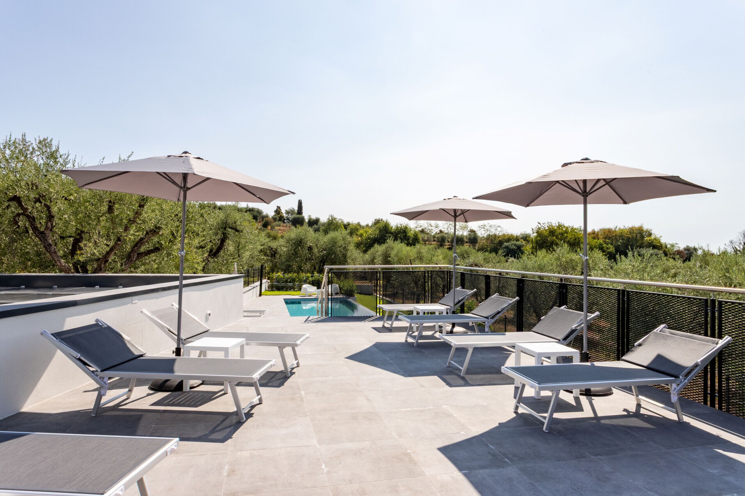 Une terrasse sur le toit avec des espaces de détente en plein air, des parasols et une piscine.