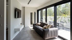 Una sala de estar moderna con un sofá, un televisor de pantalla plana y ventanas amplias.