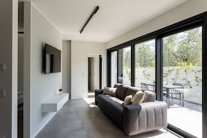 A modern living room with a sofa, a flat-screen TV, and large windows. - Casa Franzosi - Leccino Luxury (Puegnago sul Garda)