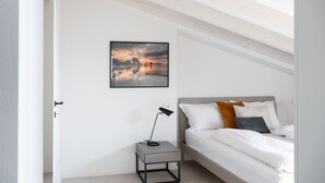 A bedroom with a bed, a bedside table, a lamp, and a framed picture on the wall.