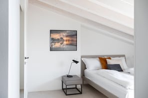 Ein Schlafzimmer mit einem Bett, einem Nachttisch, einer Lampe und einem gerahmten Bild an der Wand.