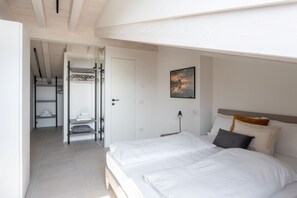 Een slaapkamer met een groot bed, een nachtkastje, een wandlamp en een schilderij.