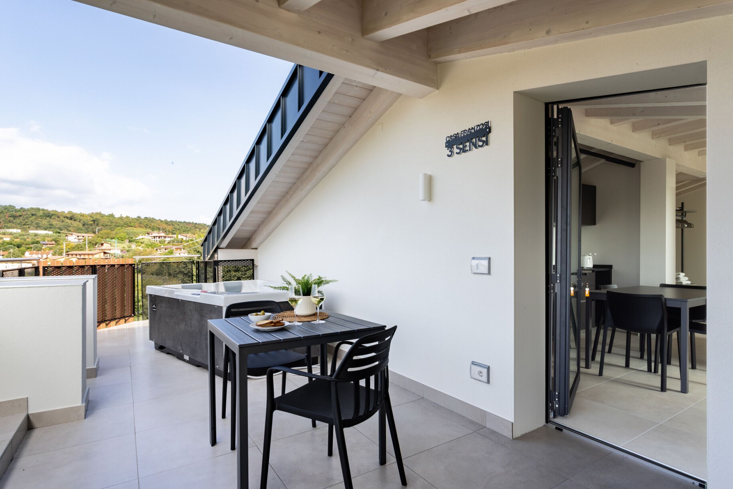 A balcony with a table, chairs, and a potted plant.