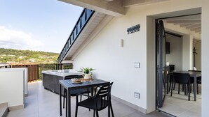 Un balcone con tavolo, sedie e una pianta in vaso.