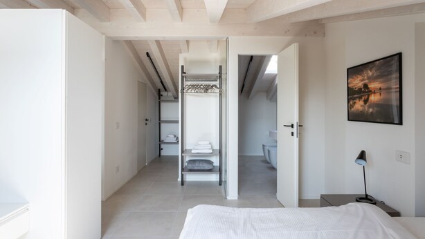 Una camera da letto moderna con un letto, un comodino, una lampada e un quadro appeso al muro.