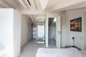 A modern bedroom with a bed, a nightstand, a lamp, and a painting on the wall.