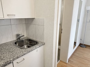 A kitchen with a stainless steel sink, white cabinets, and a granite countertop. - Cozy Studio in the Heart of Zurich - Stork 25 (Zürich)