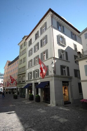 Ein mehrgeschossiges Gebäude mit einer Schaufensterfront, erkennbar an dem Prada-Schild.