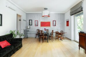 A dining area with a table and chairs, a black sofa with a red pillow, and a large window with a view. - Quasi per casa By Dimorra (Naples)