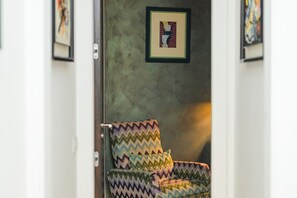 A door with a framed picture, a patterned chair, and a wall with framed artwork. - Quasi per casa By Dimorra (Naples)