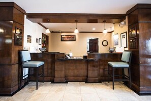 A reception area with a wooden reception desk, two chairs, a clock, and framed certificates on the walls.