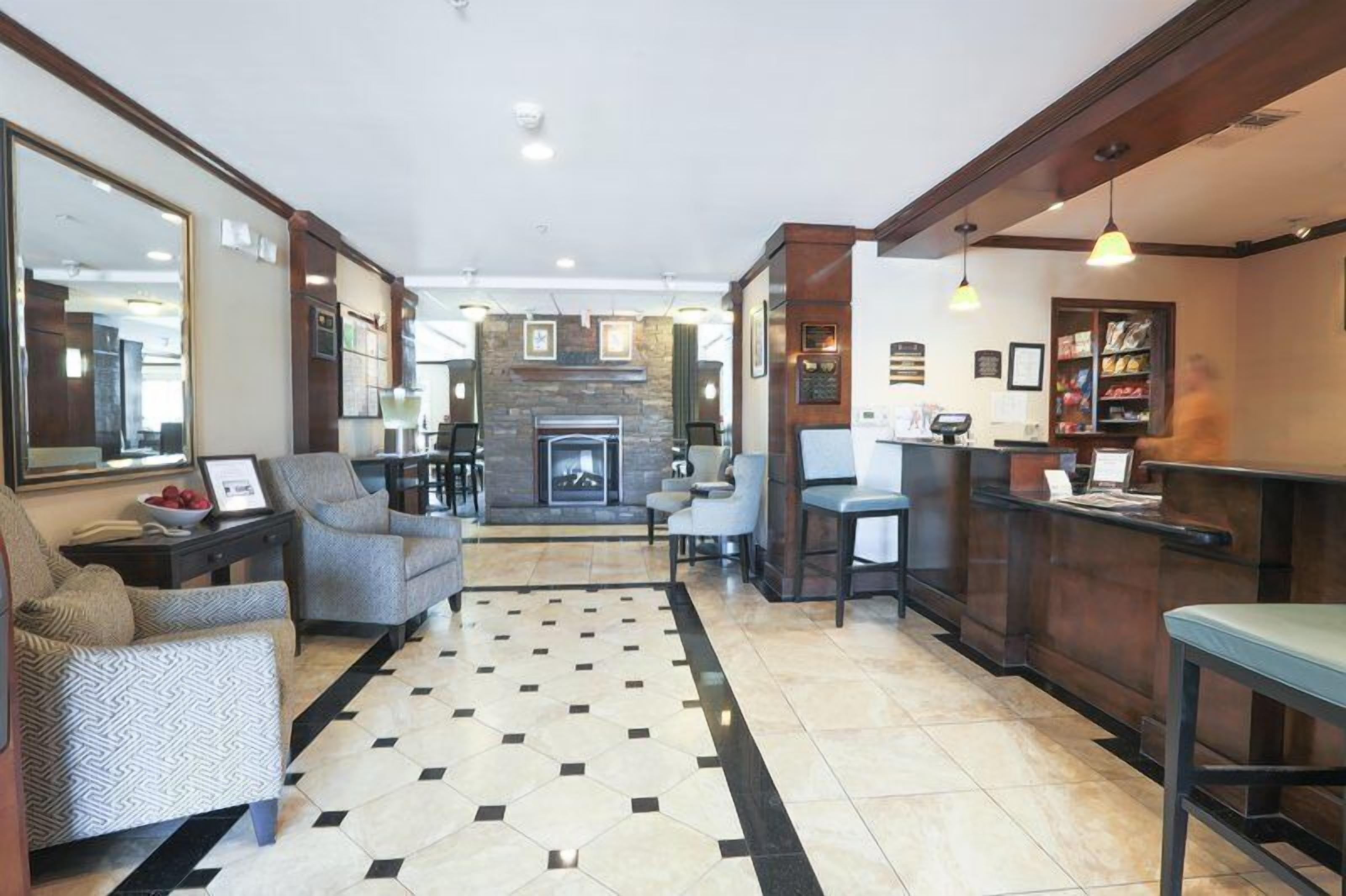 Un hall d’hôtel doté d’une cheminée, d’un espace salon et d’un comptoir d’accueil.