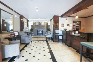 A hotel lobby with a fireplace, seating area, and a reception desk.