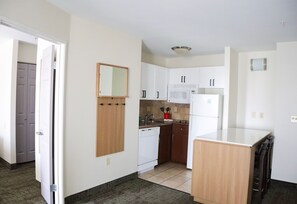A compact kitchen with white cabinets, a microwave, a dishwasher, and a small island.