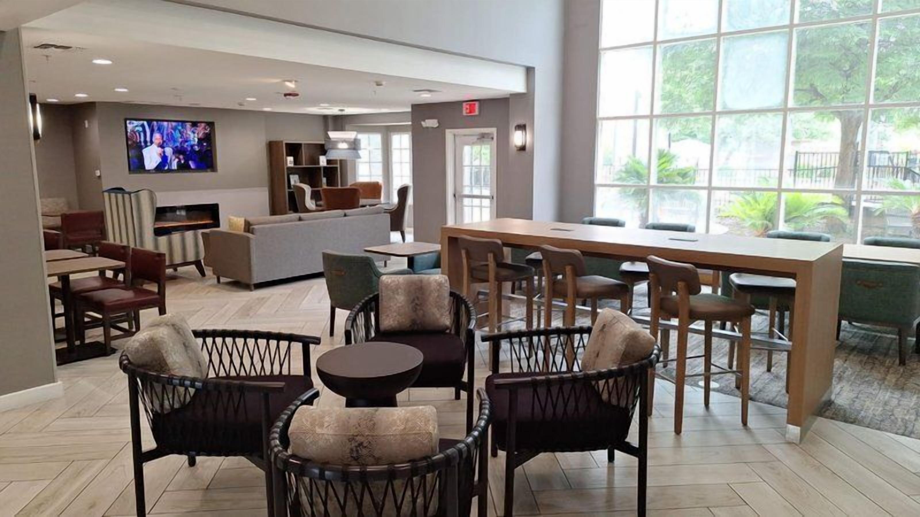 A hotel lobby with a seating area, a television, and a large window.