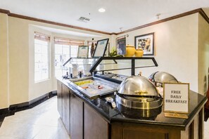Un'area buffet con un cartello che offre colazione gratuita ogni giorno, una varietà di cibi e un ambiente pulito e ben illuminato.