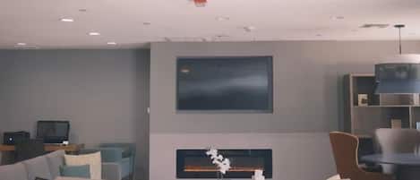 A modern living room with a flat-screen TV mounted on the wall, a fireplace, and a sofa.