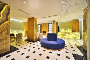 Un hall d’entrée moderne avec un espace salon central, une grande colonne et un sol à motifs.