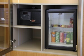Un mini-bar équipé d’un réfrigérateur pour boissons contenant des canettes de Fanta, de Sprite et de Coca-Cola, ainsi que des bouteilles de Fresca Plus et de Beypazar.
