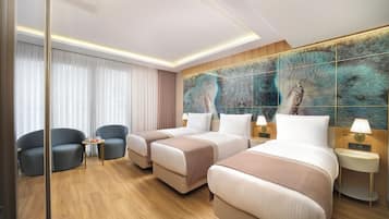 A hotel room with two beds, a sitting area with chairs, a large mirror, and a wall with a textured artwork.