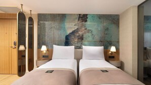 Habitación de hotel con dos camas, un cuadro abstracto grande y un armario de madera.