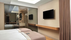 Habitación de hotel con una cama grande, un televisor montado en la pared y una puerta corredera que da a un baño.