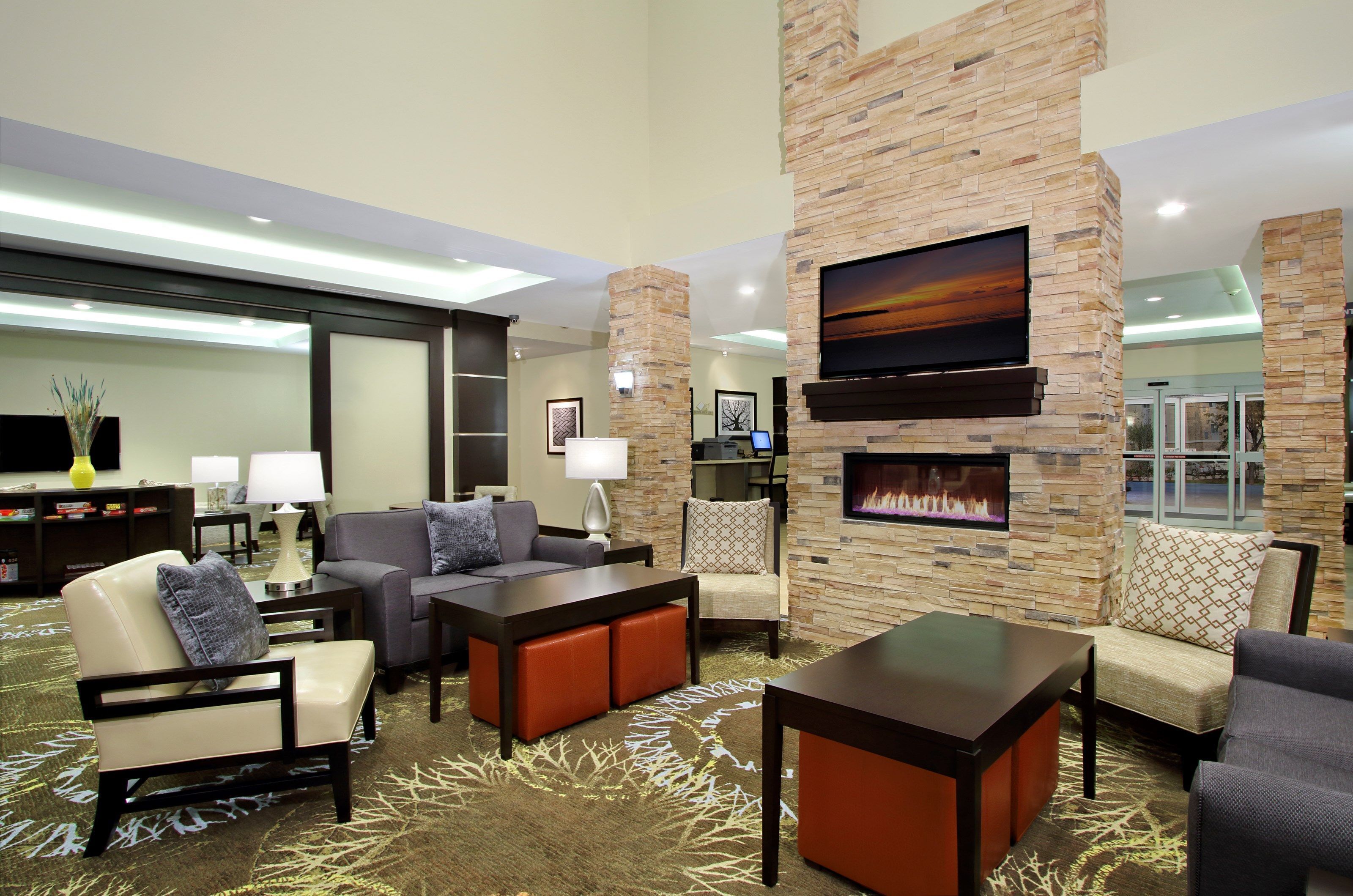 A spacious lobby with a stone fireplace, comfortable seating, and a flat-screen TV.
