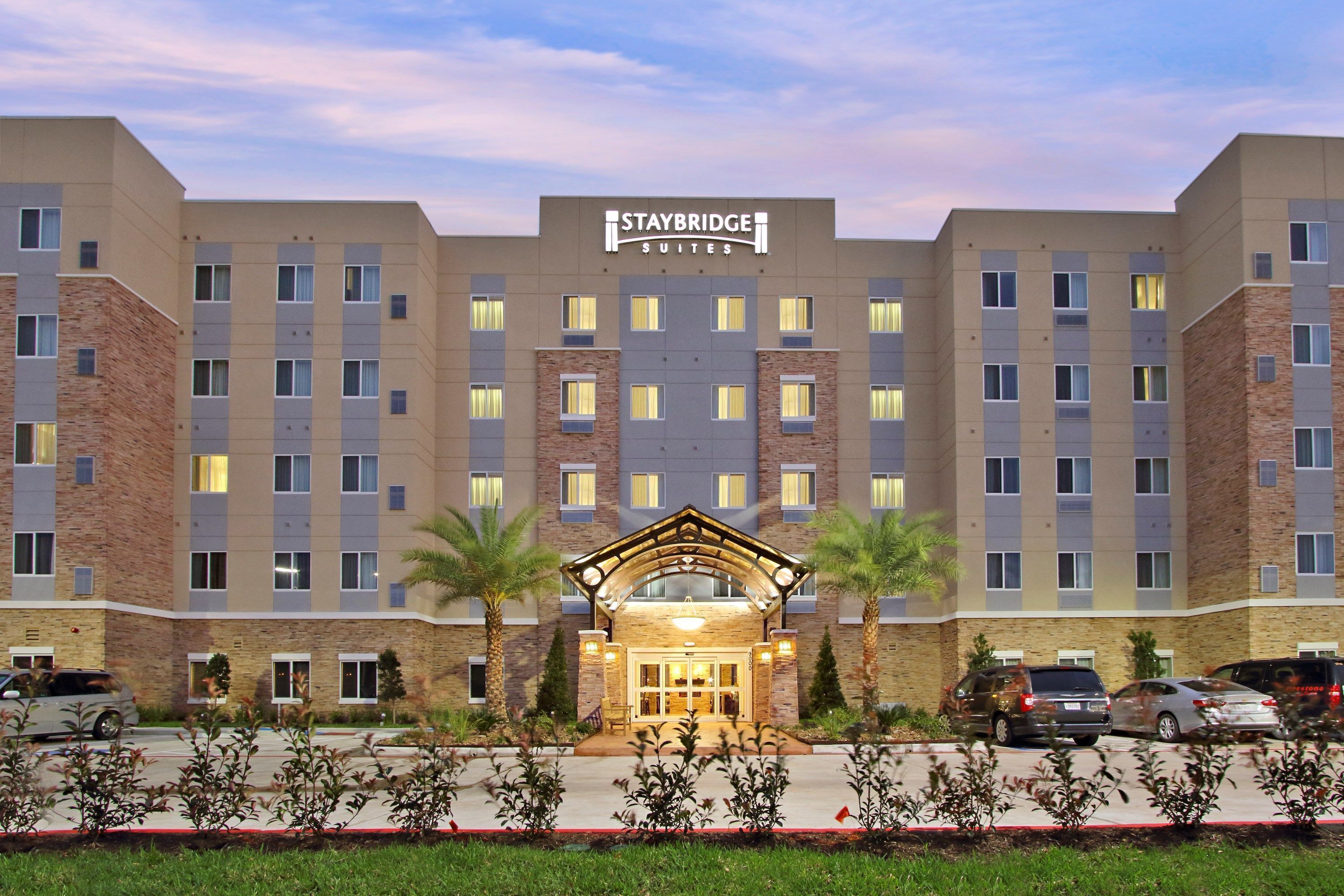 Ein Staybridge Suites Hotel mit zentralem Eingang, mehreren Etagen und einem Parkplatz.