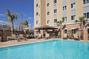 A hotel pool area with lounge chairs, palm trees, and a multi-story building in the background. - Accessible 1BR Suite w/ Tub | Hot Breakfast + Pool (Houston)